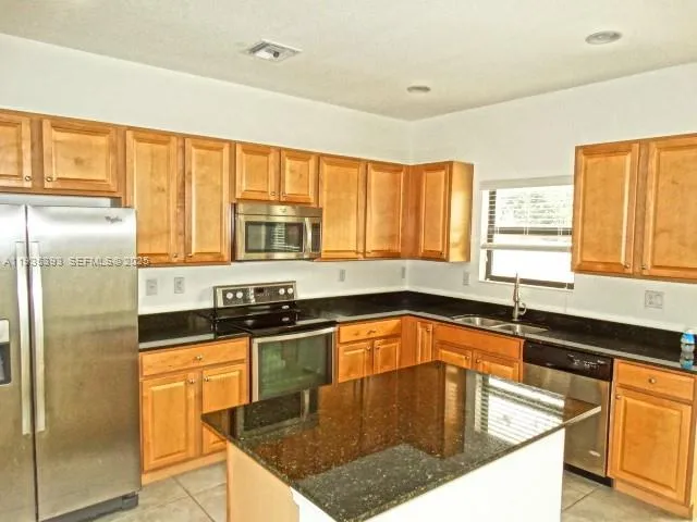 a kitchen with granite countertop a sink stainless steel appliances cabinets and a counter top space