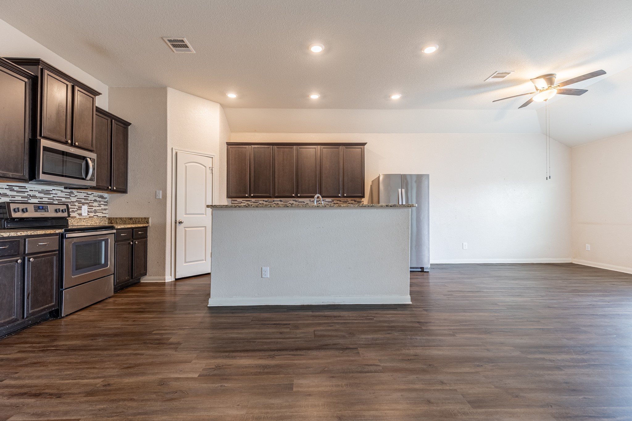 20017 Hubert R Humphrey Road Manor, TX 78653 - Photo 14 of 35 A well-appointed kitchen features stainless steel appliances, ample cabinetry, and rich wood flooring extending into the adjoining living space.