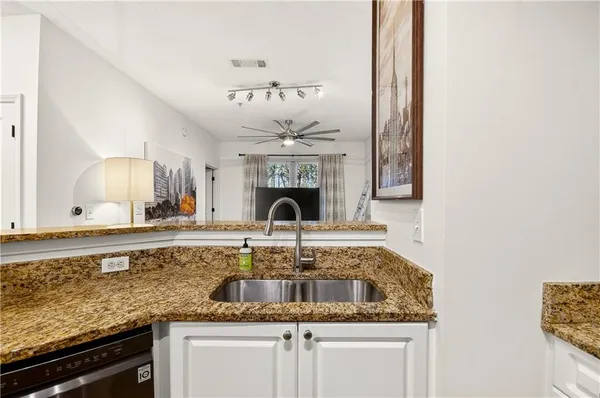 a kitchen with granite countertop a sink stainless steel appliances white cabinets and chandelier