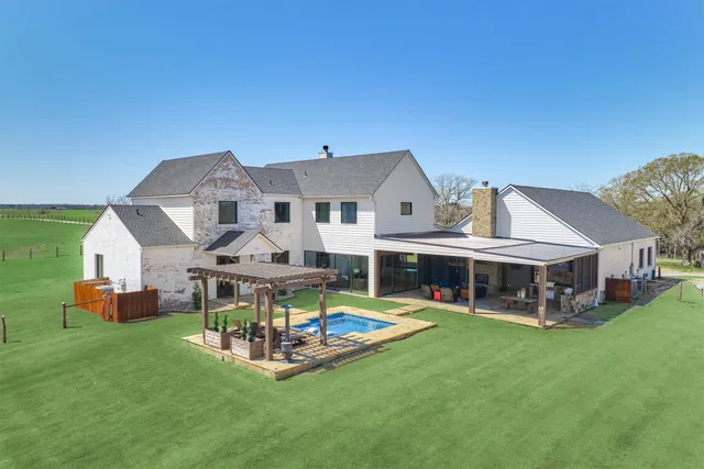 a view of a house with a big yard and large trees