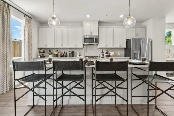 a kitchen with stainless steel appliances a dining table chairs and a refrigerator