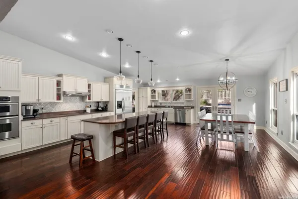 a kitchen with stainless steel appliances kitchen island granite countertop a dining table chairs and sink