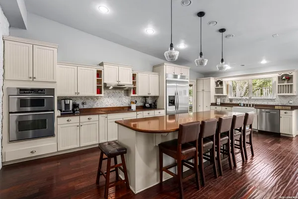 a kitchen with stainless steel appliances granite countertop a dining table chairs refrigerator and microwave