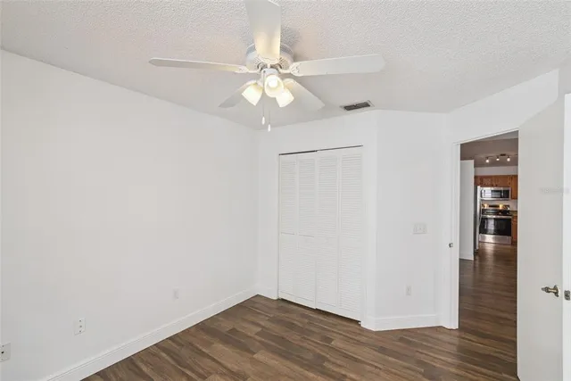 an empty room with wooden floor closet and windows