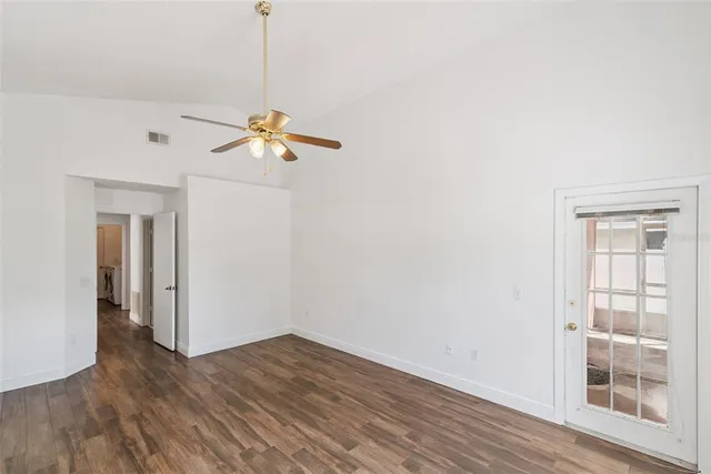 a view of an empty room with a window and wooden floor