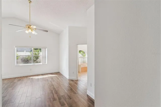 a view of an empty room with a window and wooden floor
