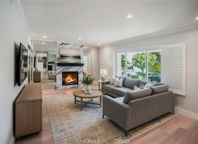 a living room with furniture kitchen view and a wooden floor