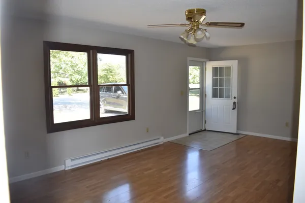 a view of an empty room with a window and wooden floor