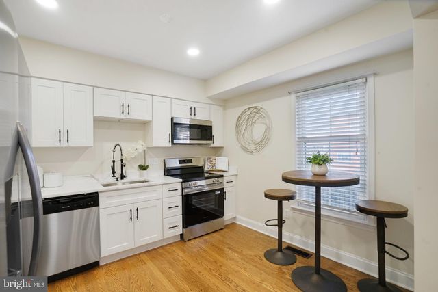 a kitchen with stainless steel appliances a stove a sink cabinets and a window