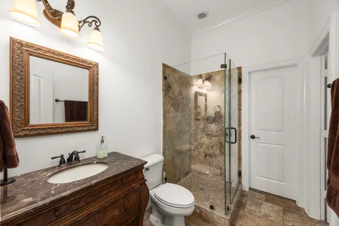 a bathroom with a granite countertop sink toilet a mirror a vanity and shower