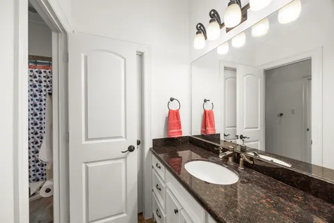 a bathroom with a granite countertop double vanity sink a mirror and shower