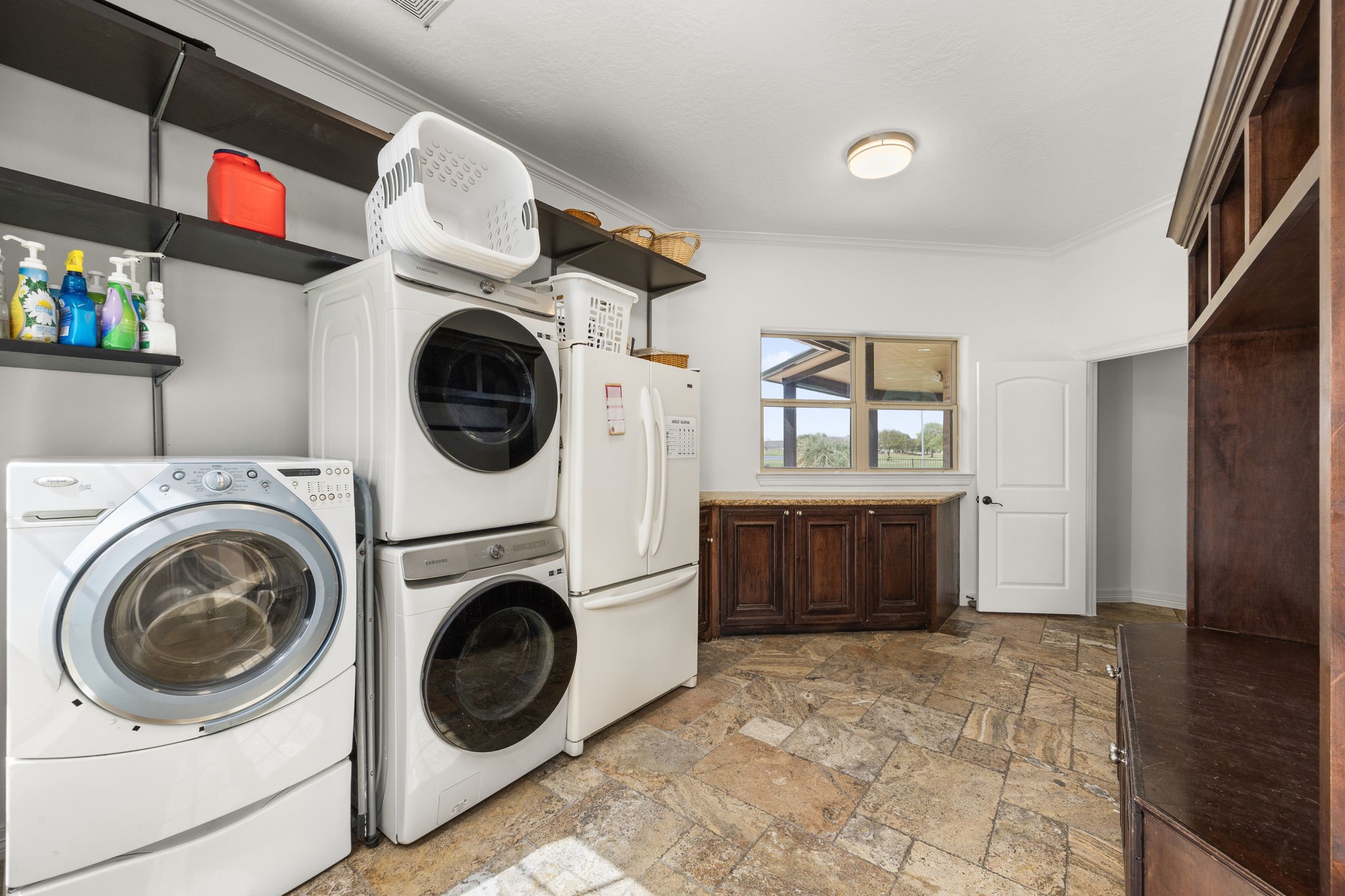4611 Oasis Point Katy, TX 77493 - Photo 29 of 41 This laundry room is more than a spot to do laundry. Large in scale and featuring the same custom cabinetry you have comes to expect, this utilitarian space is also a transition between indoor and outdoor spaces of the home. Enjoy natural light through the windows overlooking the pool, extensive storage solutions, room for your secondary fridge and built-in mudroom area with storage bench.