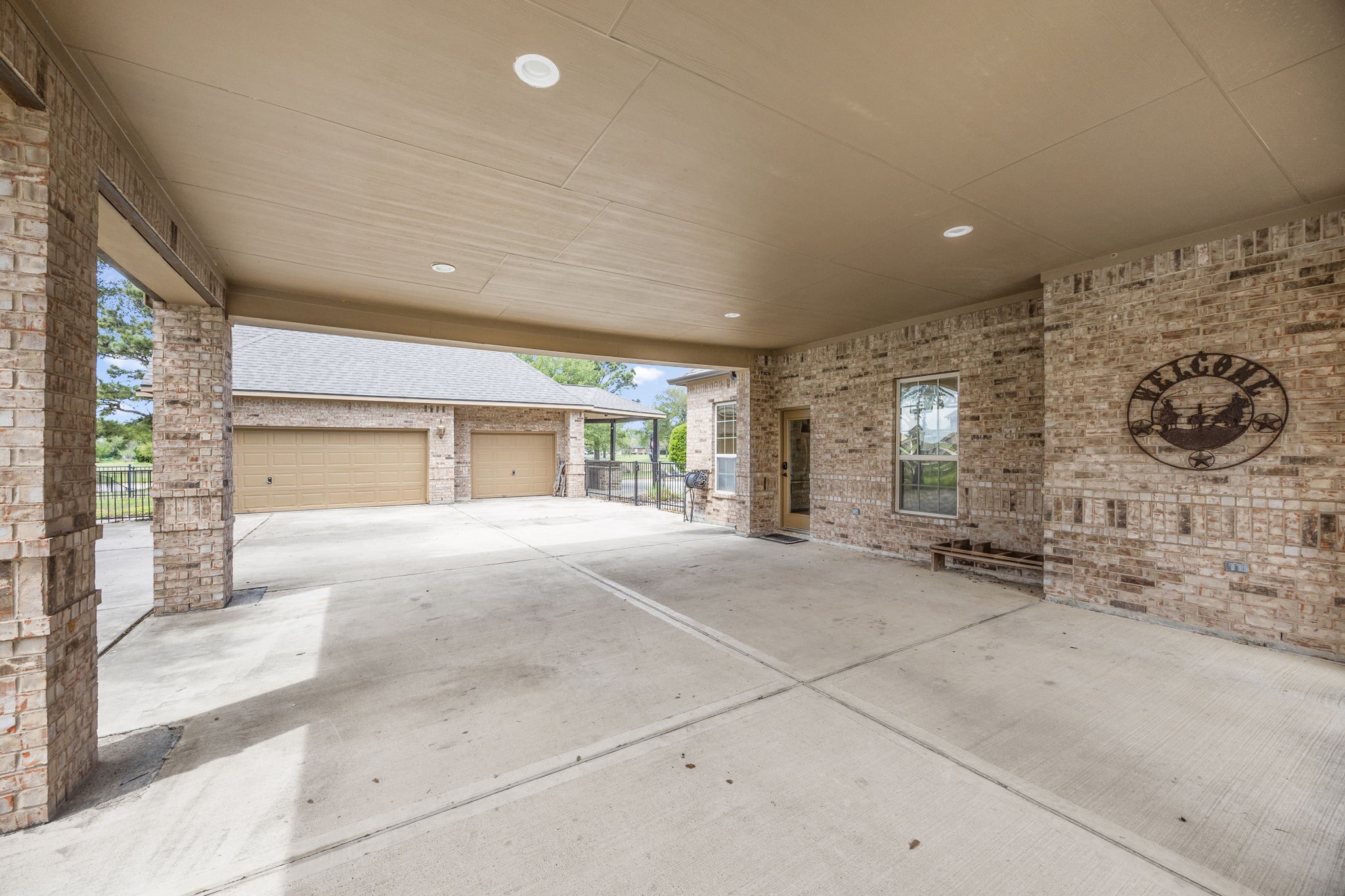 4611 Oasis Point Katy, TX 77493 - Photo 38 of 41 Aside from providing additional covered parking and boosting curb appeal, the porte cochere is a weather-safe place to unload loved ones and groceries in inclement weather. From here, you have direct access into the utility/mud room. Two parking bays are divided by brick columns and featuring recessed lighting, this functional feture of the home is also an elevated experience.