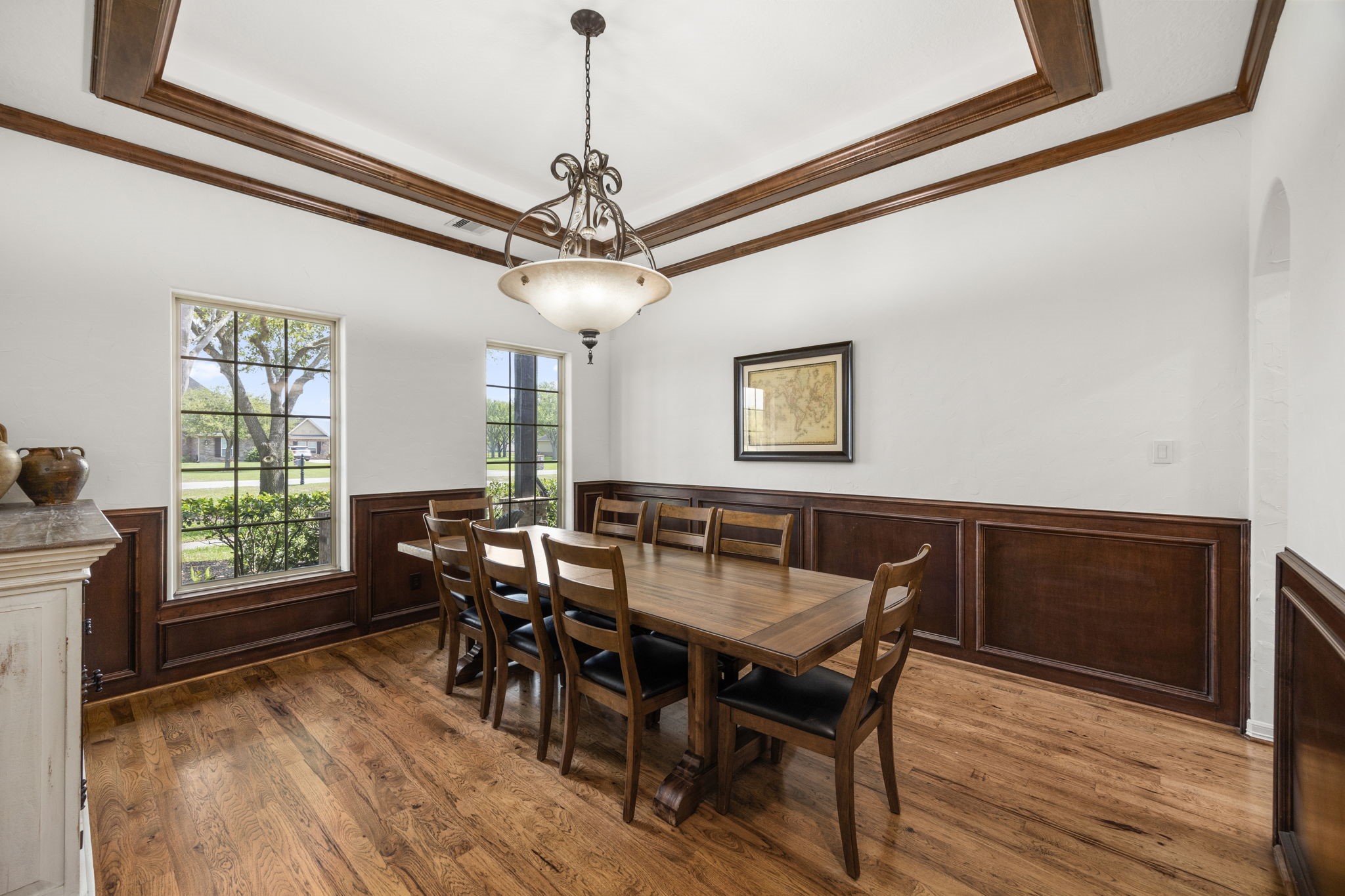 4611 Oasis Point Katy, TX 77493 - Photo 8 of 41 Hallmarks of the formal dining room include upscale millwork, hardwood flooring, and a double tray ceiling with wood trim to coordinate with the solid wood wainscotting. This entertaining space can accommodate large groups for milestone celebrations, or simply set the tone for a quiet meal overlooking the front yard and cul-de-sac on any given evening.