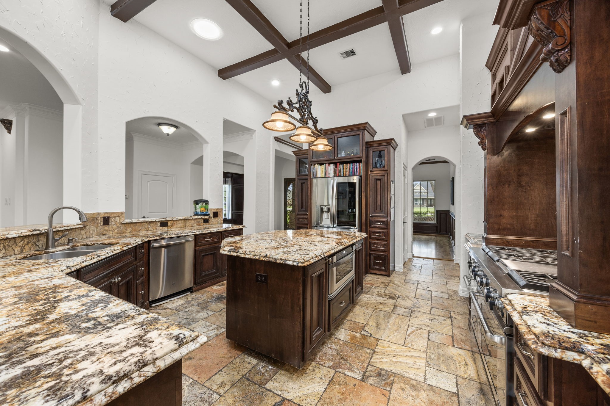 4611 Oasis Point Katy, TX 77493 - Photo 9 of 41 Thick cuts of natural stone, deep wood tones, and cabinetry selected for its timeless appeal are offset by the neutral paint in Sherwin Williams' Alabaster used throughout the home to provide visual consistency. The beams found in the office make another appearance here in the heart of this home.