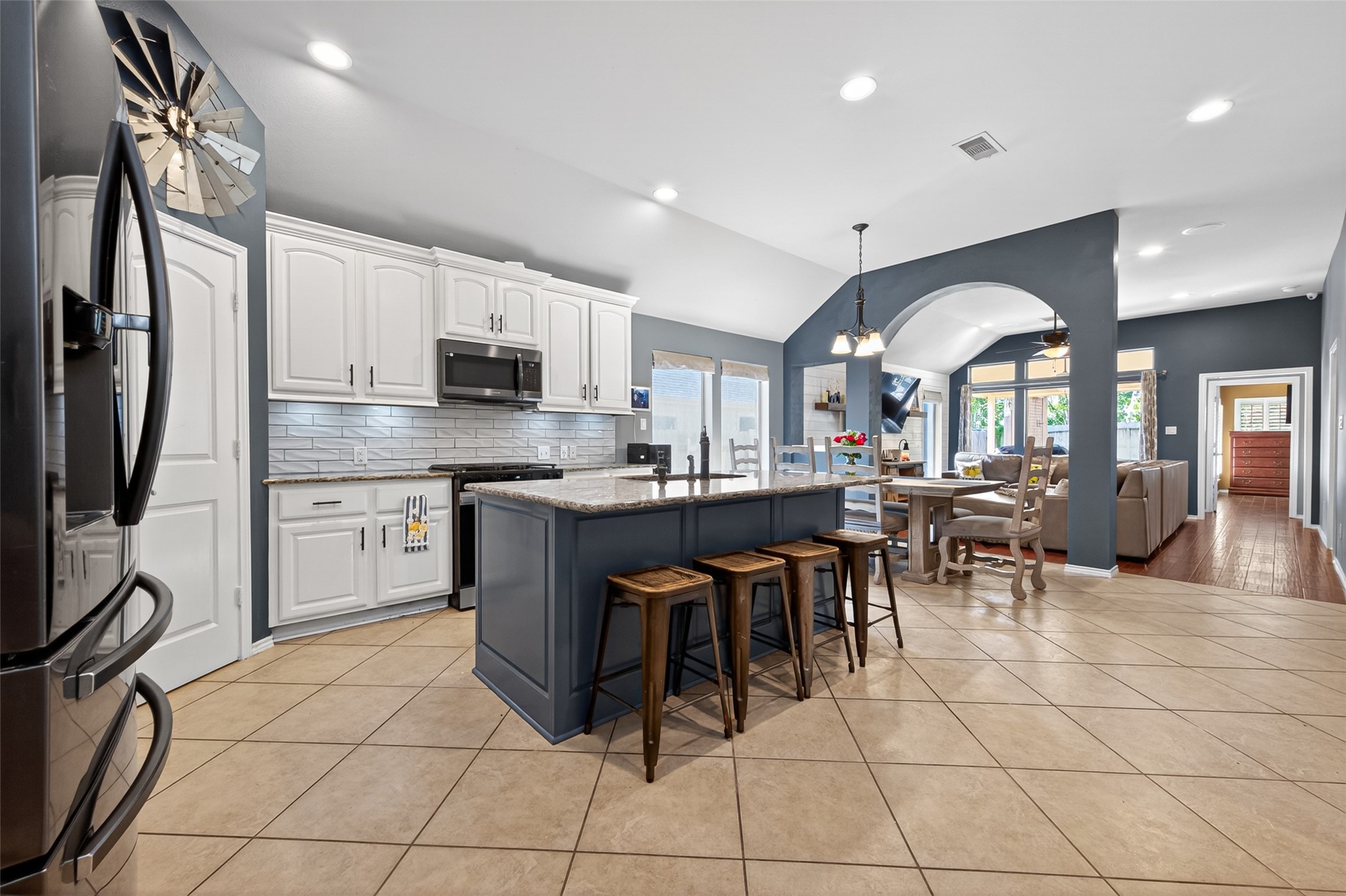 27443 Rebecca Field Lane Spring, TX 77386 - Photo 7 of 31 This spacious kitchen features modern appliances, white cabinetry, and a large island with seating. It opens to a dining area and living space, creating a bright, open-concept layout perfect for entertaining.