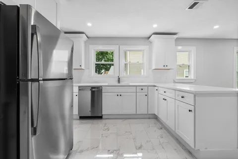 a kitchen with white cabinets and refrigerator