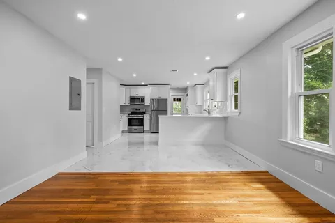 a view of a kitchen with kitchen island a sink wooden floor and a refrigerator