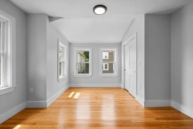 a view of an empty room with window and wooden floor