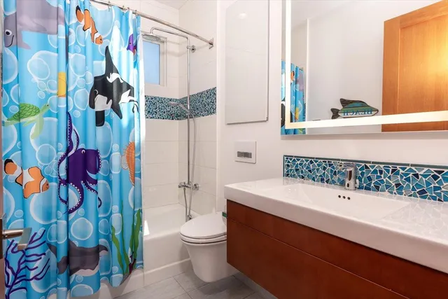 a bathroom with a bathtub sink vanity mirror and toilet