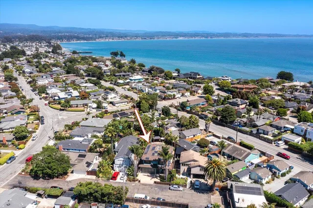 an aerial view of a city with lots of residential buildings and ocean view in back