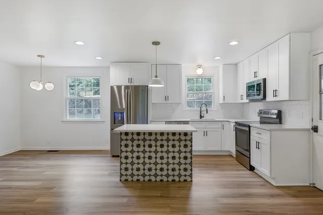 a kitchen with stainless steel appliances granite countertop a stove a sink dishwasher a refrigerator and a microwave oven with wooden floor