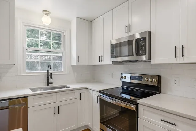 a kitchen with cabinets stainless steel appliances a sink and a window