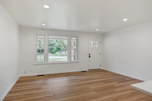 an empty room with wooden floor and windows