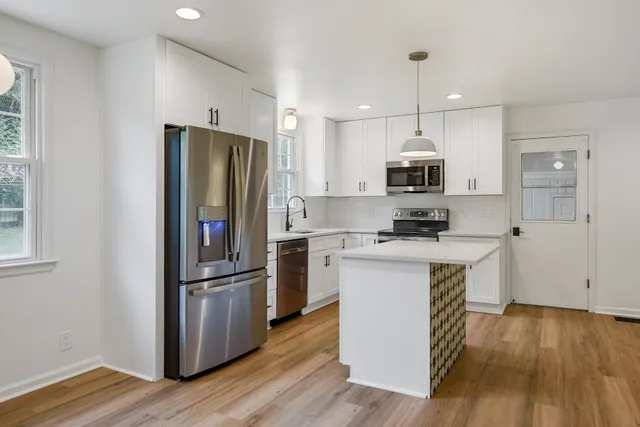 a kitchen with kitchen island wooden floors appliances and sink