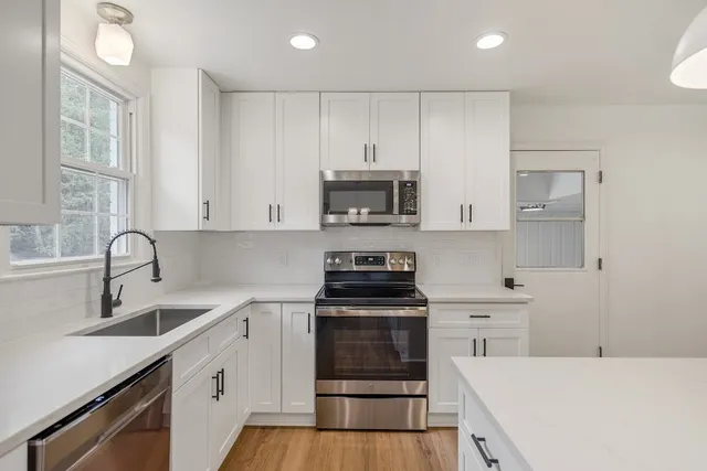a kitchen with granite countertop white cabinets and stainless steel appliances