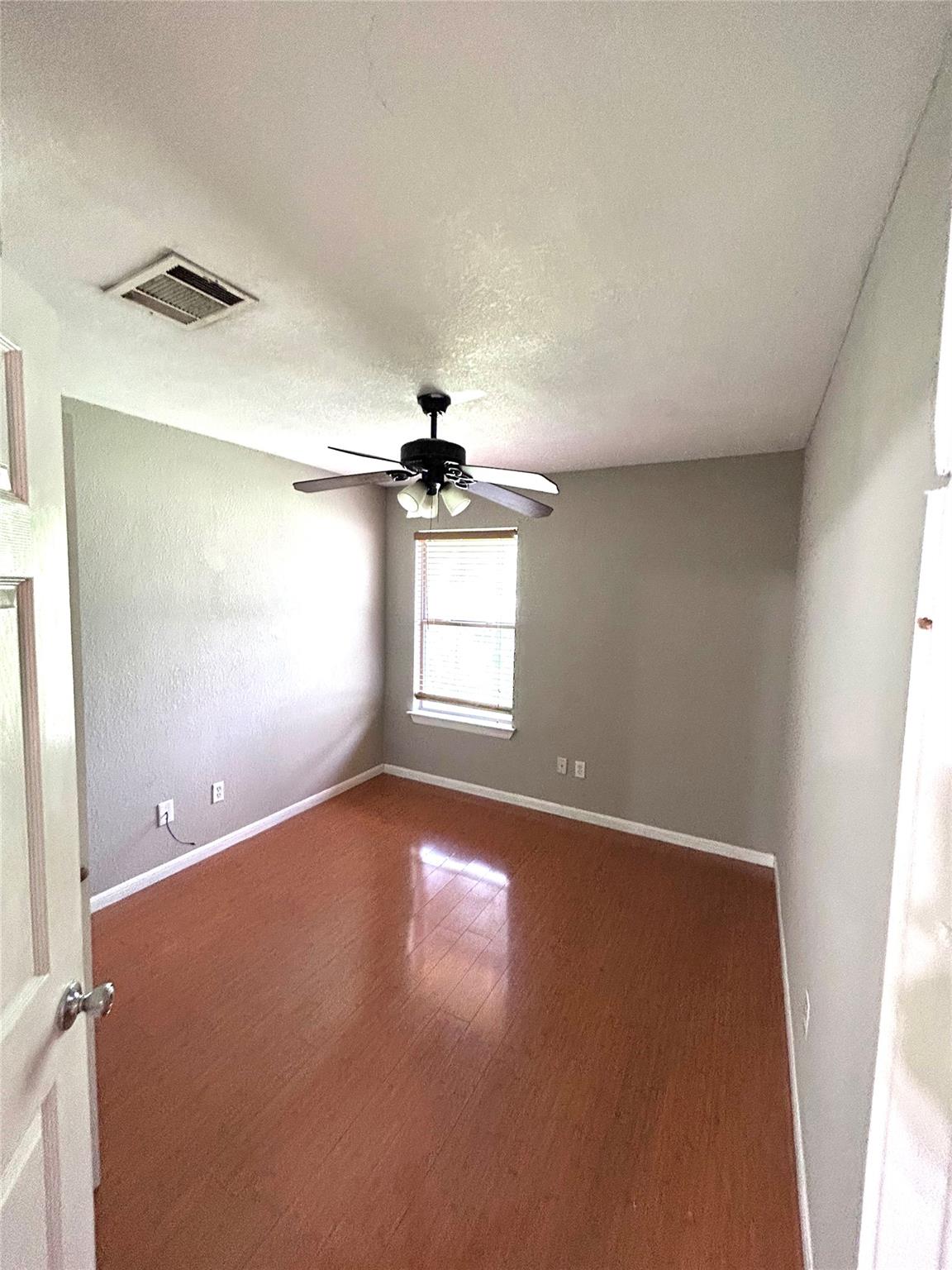 5708 Spring Meadow Road, Unit B Austin, TX 78744 - Photo 14 of 23 Unfurnished room with wood finished floors, ceiling fan, and a textured ceiling
