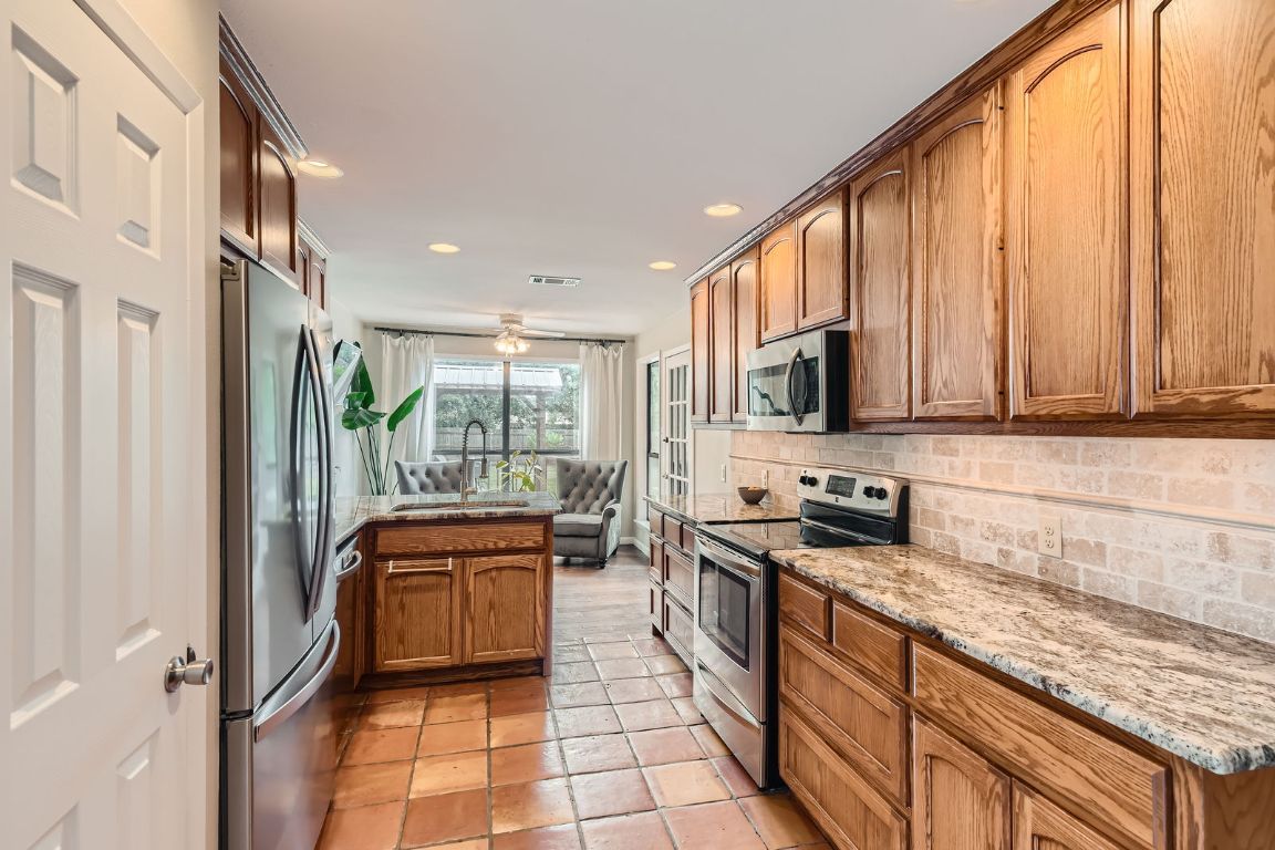 13223 Broadmeade Avenue Austin, TX 78729 - Photo 12 of 39 a kitchen with stainless steel appliances granite countertop a stove a sink and a microwave