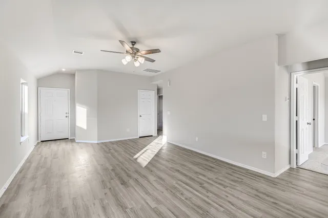 an empty room with wooden floor and ceiling fan