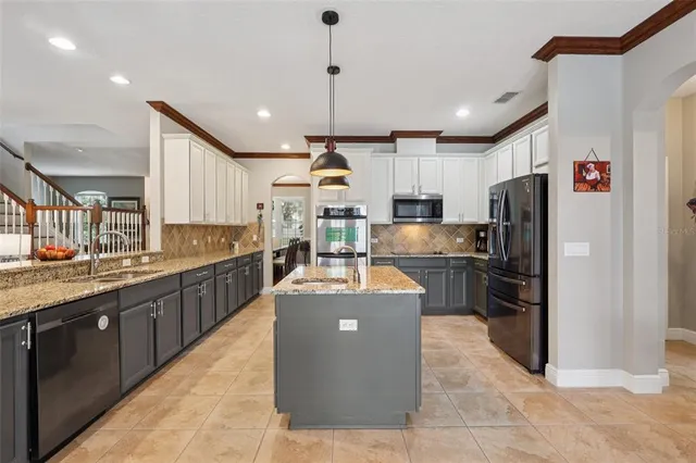 a kitchen with stainless steel appliances granite countertop a sink a refrigerator and a stove
