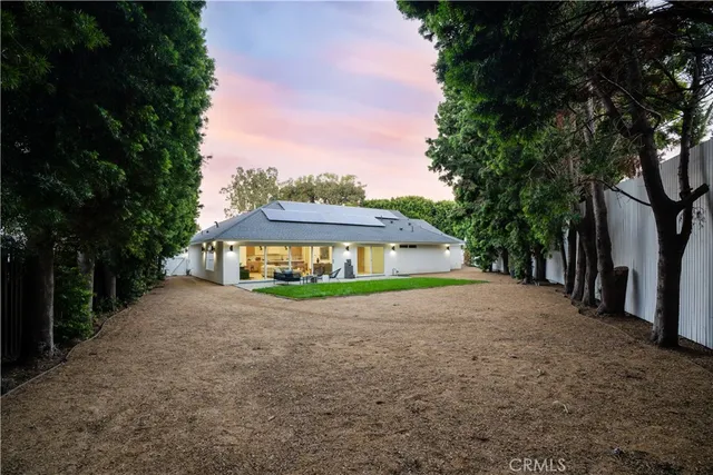 a view of a house with a yard and large tree