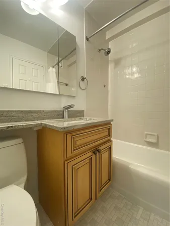 a bathroom with a granite countertop sink toilet and shower