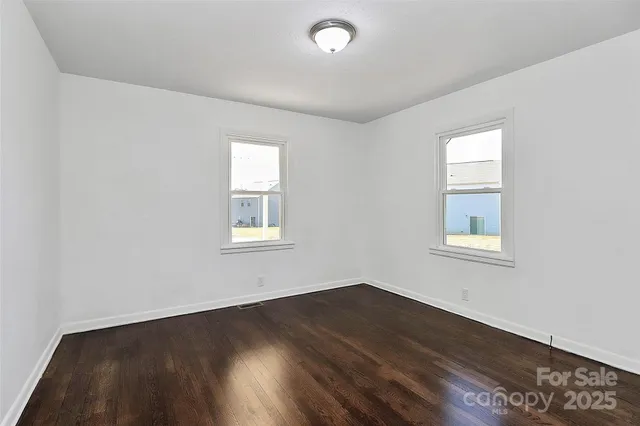 a view of a big room with wooden floor and windows