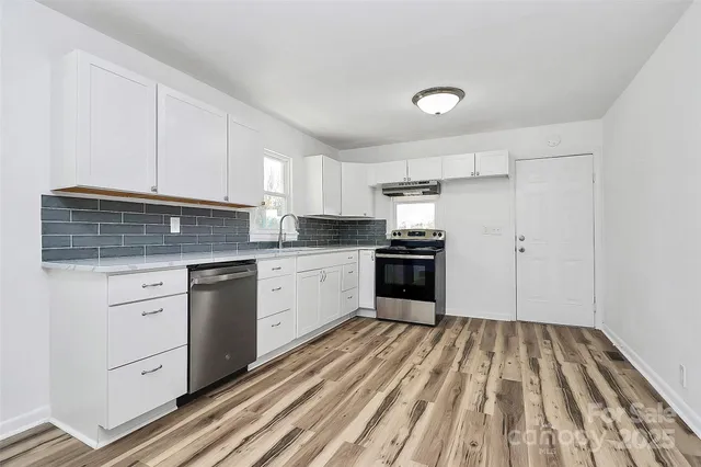 a kitchen with granite countertop white cabinets stainless steel appliances and sink