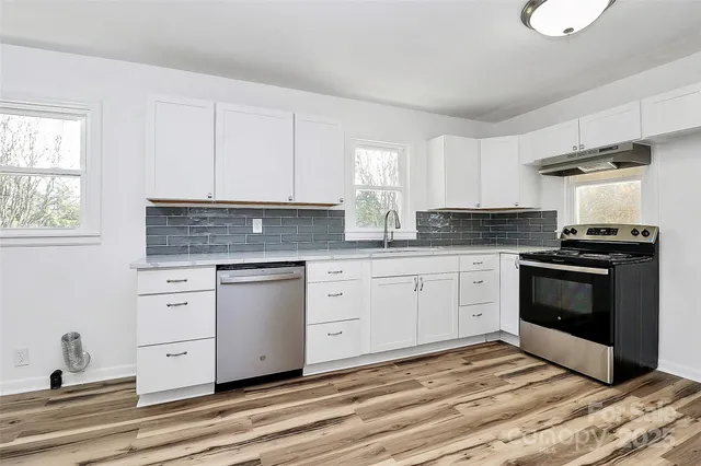 a kitchen with stainless steel appliances granite countertop a stove a sink and white cabinets