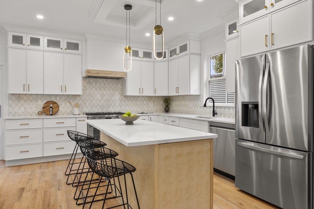 27 Coolidge Road, Unit 1 Boston, MA 02134 - Photo 8 of 41 a kitchen with stainless steel appliances a refrigerator a stove a sink dishwasher and white cabinets with wooden floor