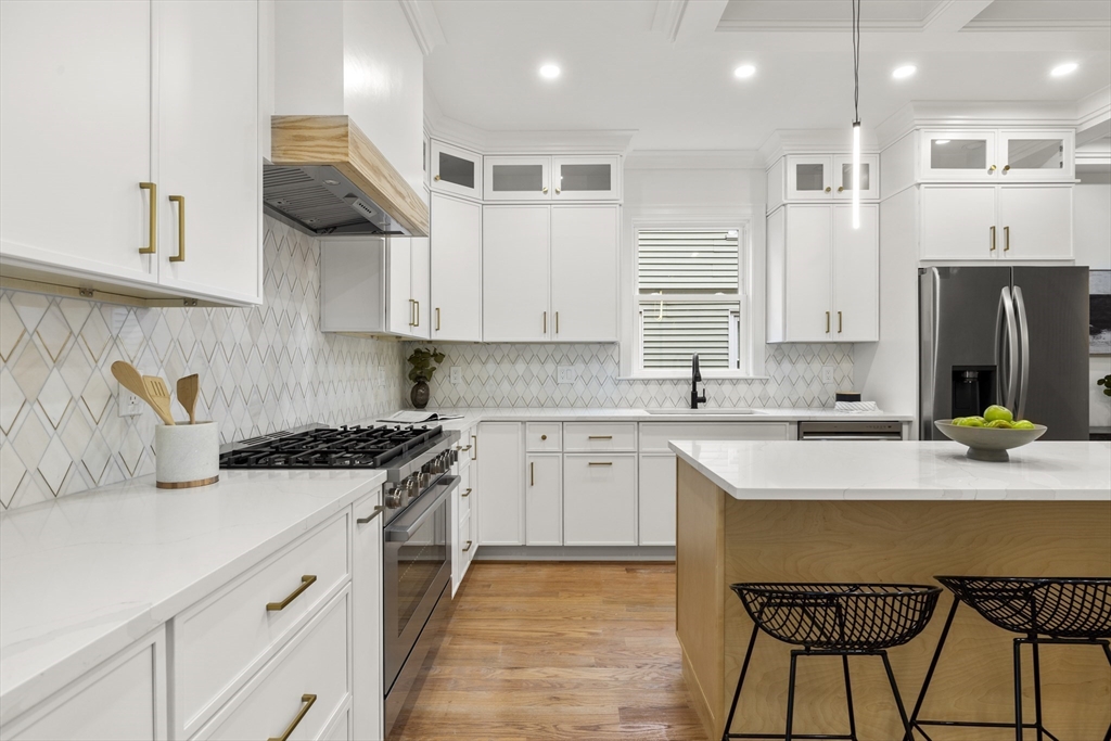 27 Coolidge Road, Unit 1 Boston, MA 02134 - Photo 9 of 41 a kitchen with kitchen island granite countertop a stove a sink a refrigerator and white cabinets with wooden floor
