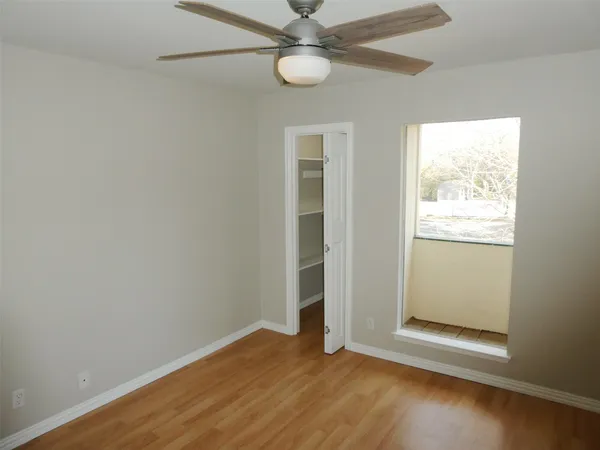 an empty room with wooden floor fan and windows