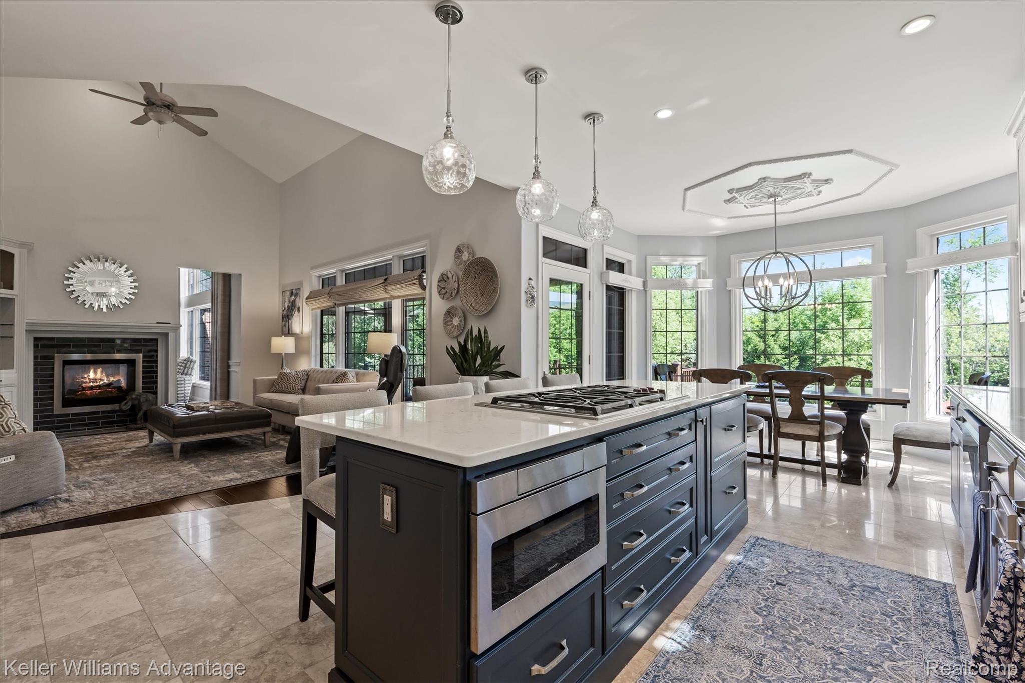 22878 Tree Top Court South Lyon, MI 48178 - Photo 8 of 75 Open-concept kitchen featuring a dark-toned island with a built-in gas cooktop, stainless steel microwave drawer, and stone-finish countertops