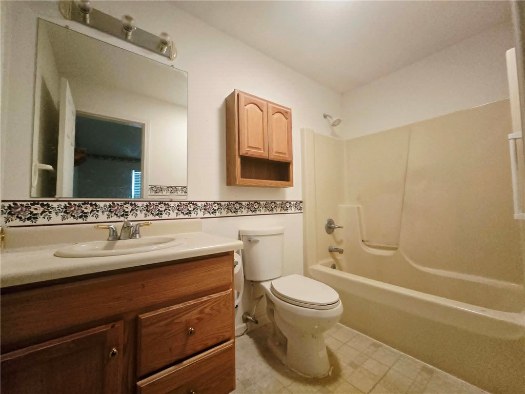 202 Keith Lane Seneca, SC 29678 - Photo 13 of 23 A well-lit bathroom features a single vanity, a toilet, and a bathtub with shower.