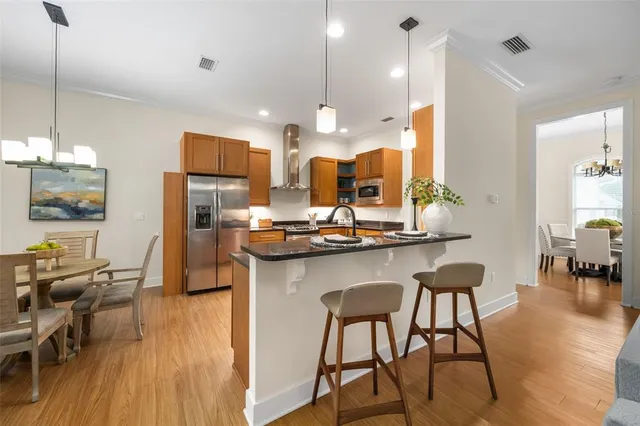 a kitchen with stainless steel appliances kitchen island granite countertop a table chairs and a refrigerator