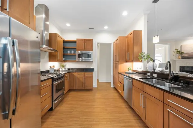 a large kitchen with stainless steel appliances granite countertop a stove a sink dishwasher a refrigerator and a oven with wooden floor