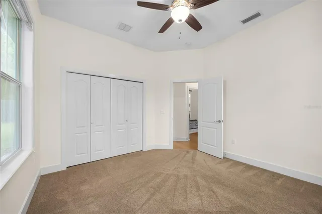 a view of an empty room and chandelier fan