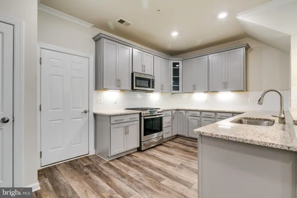a kitchen with granite countertop white cabinets and stainless steel appliances