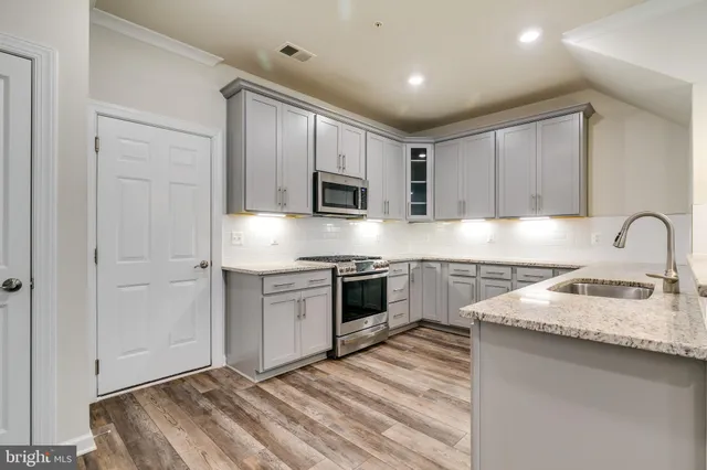 a kitchen with granite countertop white cabinets and stainless steel appliances