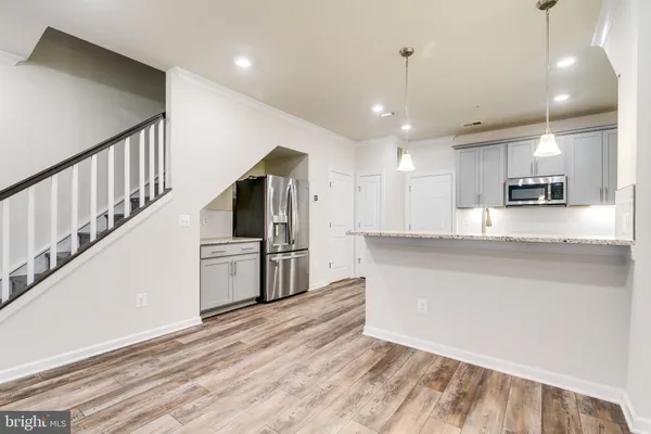 a kitchen with stainless steel appliances kitchen island granite countertop a refrigerator a stove and white cabinets with wooden floor